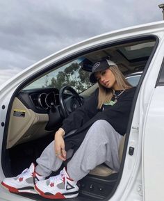 a woman sitting in the driver's seat of a car with her feet up