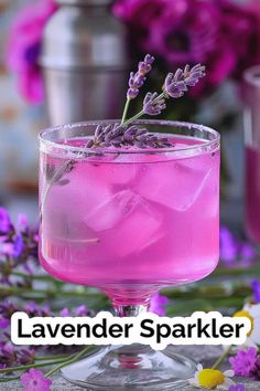 lavender sparkler cocktail in a glass with ice and flowers around the rim on a table