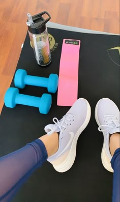 a woman's feet with blue and pink dumbs next to a pair of shoes