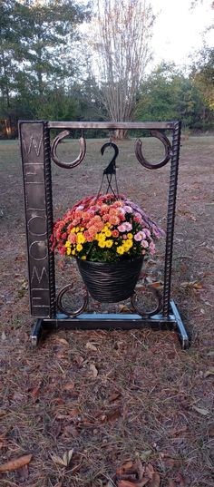 a basket with flowers in it sitting on top of a metal stand that says welcome