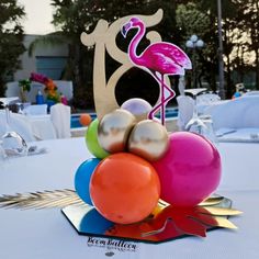 a flamingo centerpiece on top of a table with balloons