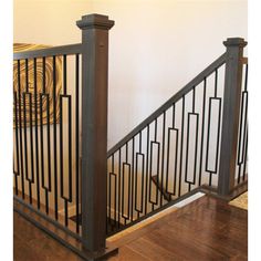 an iron stair railing with wood handrails in a home setting, against a white wall and hardwood flooring