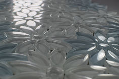 an intricately designed table top made out of white plastic flowers and leaves, with the sun shining through the petals