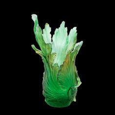 a glass vase with green flowers in it on a black background and the bottom half turned upside down