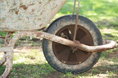 an old rusty wheelbarrow sitting in the grass