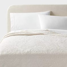 a bed with white sheets and pillows on it