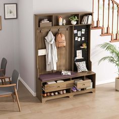 a room with a chair, table and coat rack on the wall next to stairs