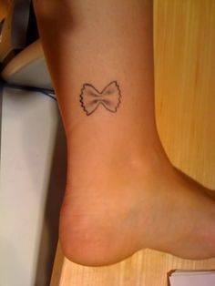 a woman's foot with a small bow tattoo on her left ankle and right leg