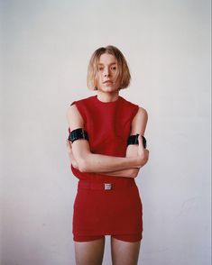 a woman in a red dress with her arms crossed