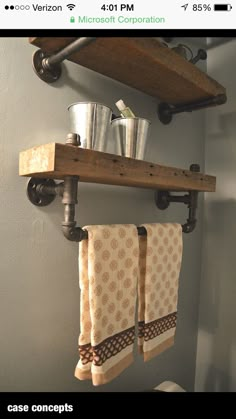 two towels hanging on the wall above a toilet in a bathroom with metal buckets