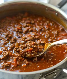 a ladle full of chili and meat in a pot