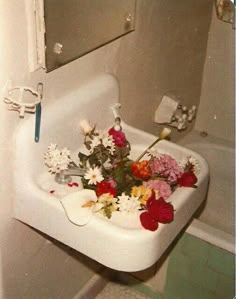 a bunch of flowers that are sitting in a sink next to a bath room mirror