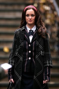 a woman in a suit and tie is walking down the street with her hand on her hip