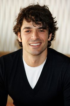 a man with curly hair smiling at the camera