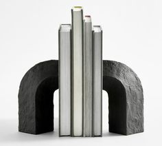 three books stacked on top of each other in front of a black arch and white background