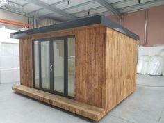 a small wooden building sitting inside of a large room with lots of windows and doors