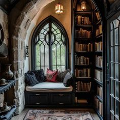 an arched window in the corner of a room with bookshelves and a bench