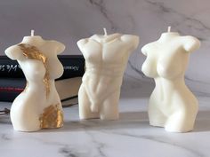 three candles that are shaped like female torsos