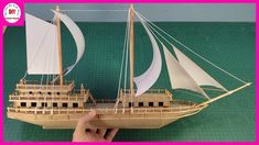 a wooden model of a boat on a green mat with a hand holding it up