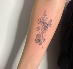 a woman's arm with a tattoo on it that has flowers and butterflies on it