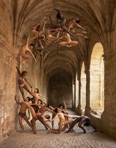 several nude men and women are dancing in an old building with stone floors, arches and ceiling