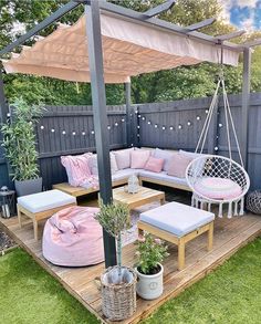 an outdoor patio with pink and white furniture on the deck, potted plants and hanging hammock