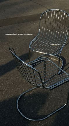 a metal chair sitting on top of a parking lot next to a sidewalk with no one in it