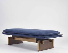 a large blue pillow sitting on top of a wooden bench with metal legs and feet