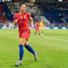 a female soccer player is running on the field with her ball in front of her