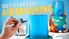 someone is decorating a cake with blue icing and orange flowers on it, while the video title reads get started airbrushing