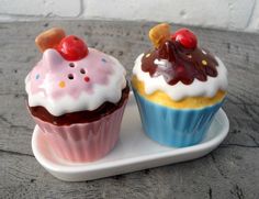 two cupcakes with frosting and cherries on top sit on a plate