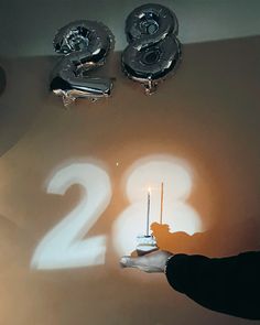 a person holding a lit candle in front of the number twenty two candles on a wall