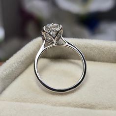 a diamond ring sitting on top of a white velvet cushion in a box with its lid open