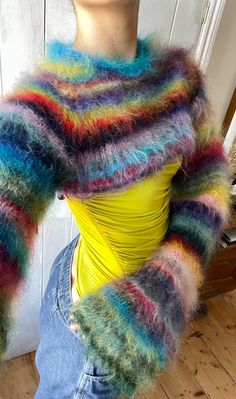 a mannequin wearing a multicolored sweater and jean pants with her hands on her hips