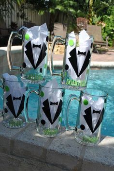 four glass mugs decorated with black and white tuxedos are sitting in front of a pool