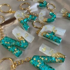 several different types of key chains with gold and blue glitters on them, sitting on a table