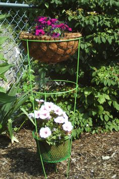 three tiered planter stands with flowers in them next to a chain link fence