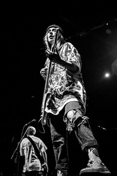 a man standing on top of a stage while holding a skateboard in his hand