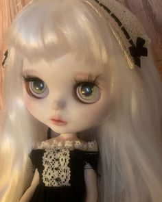 a doll with long white hair wearing a black dress and lace on it's head