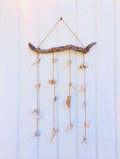 a wind chime hanging on the side of a white wall with shells and branches