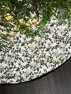 a white and green table cloth on top of a wooden table next to a potted plant