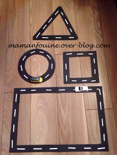 a toy car race track set made out of cardboard on the floor with a wooden background