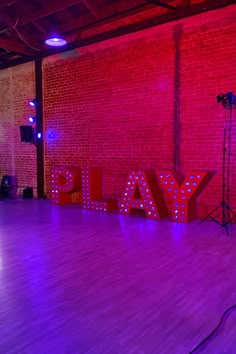 an empty dance floor in front of a red brick wall with the word yals lit up