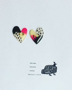 two heart shaped brooches sitting on top of a piece of paper next to each other