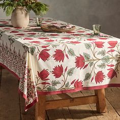 a table covered with a red and white floral print cloth next to a potted plant