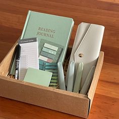 a wooden desk with a book, pen and papers in it