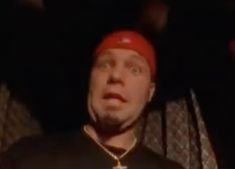 a man in a red hat and black shirt is making a face with his mouth wide open