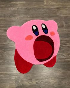 a pink rug with an open mouth on top of a wooden floor in the shape of a pig