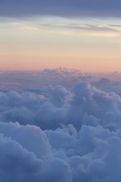 the sky is filled with fluffy clouds as the sun sets over the horizon in the distance