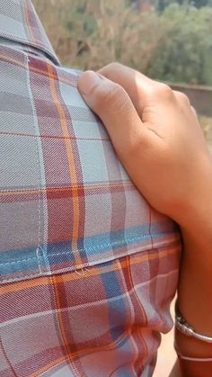 a person with their hand on the back of a plaid shirt